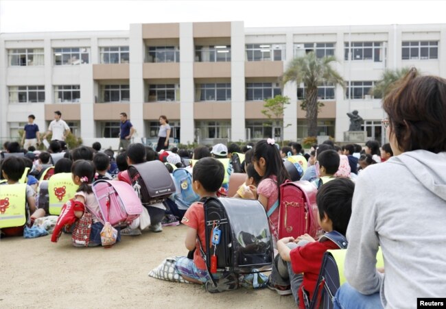 Estudiantes sentados en un patio de recreo después de ser evacuados del edificio escolar tras un terremoto en Ikeda, Osaka, oeste de Japan, el lunes, 18 de junio de 2018.