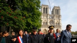 El ministro del Interior francés, Christophe Castaner, a la derecha, la alcaldesa de París, Anne Hidalgo, a la izquierda, y otros funcionarios, caminan por la catedral de Notre Dame.