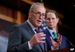 FILE - Senate Minority Leader Chuck Schumer of New York and Sen. Ron Wyden, D-Ore., discuss the Republican tax plan during a news conference on Capitol Hill in Washington, Sept. 27, 2017.