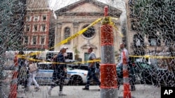 New Yorkers pass a shattered storefront window on W. 23rd St. in Manhattan. The window was hit by shrapnel from the bomb that exploded across the street Saturday evening