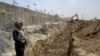 FILE - In this May, 16, 2014 file photo, a Pakistani border guard stands alert as an excavator digs a trench along Pakistan Afghanistan border at Chaman post in Pakistan.