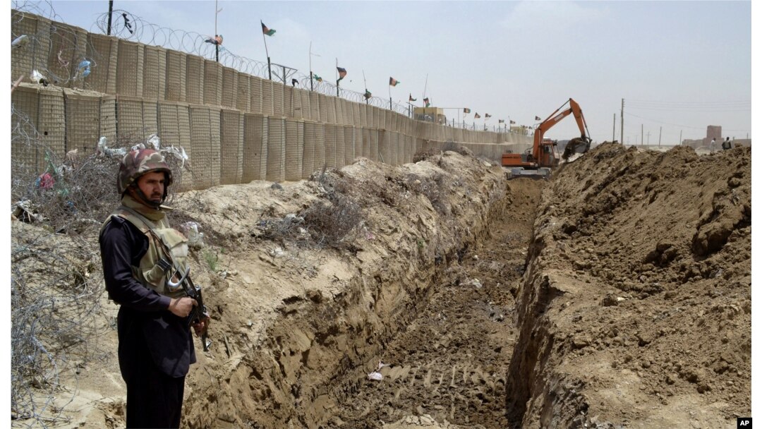 FILE - A Pakistani border guard watches as an excavator digs a trench along Pakistan's border with Afghanistan, at Chaman post in Pakistan, May, 16, 2014.