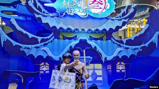 中国网络游戏展览会ChinaJoy2019年8月2日在上海展出期间一名女子与中国一个电子游戏中的一角色扮演者合影。 