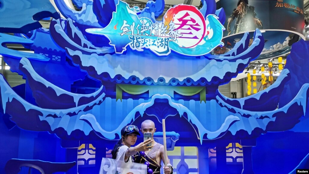 中国网络游戏展览会ChinaJoy2019年8月2日在上海展出期间一名女子与中国一个电子游戏中的一角色扮演者合影。(photo:VOA)