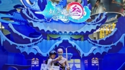 中国网络游戏展览会ChinaJoy2019年8月2日在上海展出期间一名女子与中国一个电子游戏中的一角色扮演者合影。