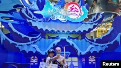 中国网络游戏展览会ChinaJoy2019年8月2日在上海展出期间一名女子与中国一个电子游戏中的一角色扮演者合影。