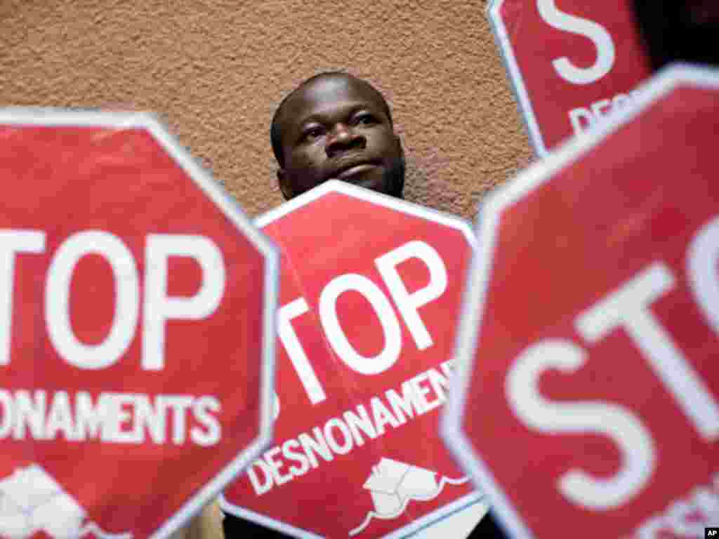 Ghanaian Wilson Yaw is seen among banners against evictions during a protest to stop the eviction of Meziane Sefioune, 34, a Moroccan citizen who is unable to pay his mortgage in Salt, Girona, Spain, Friday, Oct. 7, 2011. Dozens of evictions have been blo