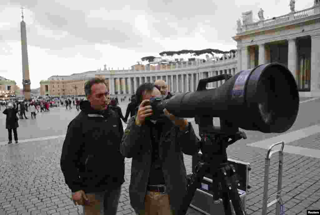 Reuters photographers Dylan Martinez (R) and Tony Gentile test a 1200-1700mm super-telephoto zoom lens, trained on the balcony of Saint Peter's Basilica where a new pope will appear after his election, a day before the beginning of the conclave at the Vatican, March 11, 2013.