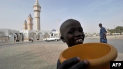 FILE - A young talibe raises a begging bowl in front of the grand mosque in Touba, in the central region of Senegal, Feb. 23, 2012. 