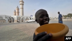 FILE - A young talibe raises a begging bowl in front of the grand mosque in Touba, in the central region of Senegal, Feb. 23, 2012. 