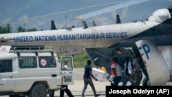 Des personnes chargent des fournitures d'urgence de Médecins Sans Frontières dans un hélicoptère des Nations Unies à destination de la ville ravagée par le séisme Les Cayes, à l'aéroport Toussaint Louverture à Port-au-Prince, Haïti, le 15 août 2021. (AP Photo/Fernando Llano)