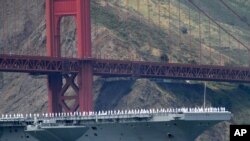 Los marineros del portaviones USS Nimitz saludan desde el puente de la nave al pasar bajo el puente Golden Gate durante la celebración del 75 aniversario.