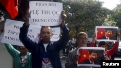 Protesters hold marked images of Chinese President Xi Jinping and anti-China signs during a protest ahead of his visit to Vietnam, on the street in Hanoi, Nov. 3, 2015. 