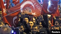 Demonstranti sa turskim zastavama i likom turskog predsednika Redžepa Tajipa Erdogana okupljeni ispred turskog konzulata kako bi poželeli dobrodošlicu turskoj ministarki za porodicu, Fatmi Betul Sajan Kaji, koja je odlučila da putuje u Roterdam kopnenim putem nakon što su turskog ministra inostranih poslova Mevluta Čavušoglua holandske vlasti sprečile da sleti u Roterdam, Holandija, 11. mart 2017. (REUTERS/Yves Herman - RTX30MBF)