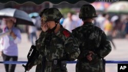 FILE - Chinese paramilitary police stand watch at a Beijing railway station, guarding against attacks by Uighur militants, Sept. 3, 2014.