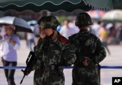 FILE - Chinese paramilitary police stand watch at a Beijing railway station, guarding against attacks by Uighur militants, Sept. 3, 2014.