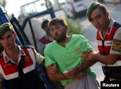 Turkish gendarmeries escort one of the 11 fugitive commandos who were involved in a bid to seize President Recep Tayyip Erdogan during a failed coup attempt last month, as he arrives at the police headquarters in Mugla, Turkey, Aug. 1, 2016.