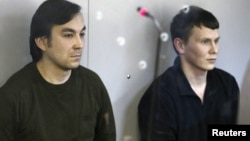 Yevgeny Yerofeyev (L) and Alexander Alexandrov, Russian servicemen arrested last May on terrorism charges related to the separatist conflict in eastern Ukraine, looks from a glass-walled cage during a court hearing in Kyiv, Ukraine, April 18, 2016.