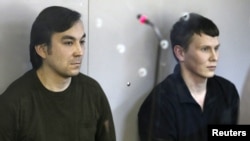 Yevgeny Yerofeyev (L) and Aleksander Aleksandrov, Russian servicemen arrested last May on terrorism charges related to the separatist conflict in eastern Ukraine, looks from a glass-walled cage during a court hearing in Kyiv, Ukraine, April 18, 2016.
