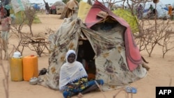 FILE - A woman is seen sitting in front of a tent in the Assaga refugee camp, set up by the U.N. for Nigerian refugees who fled to southeast Niger to escape Boko Haram militants, Sept. 16, 2015.