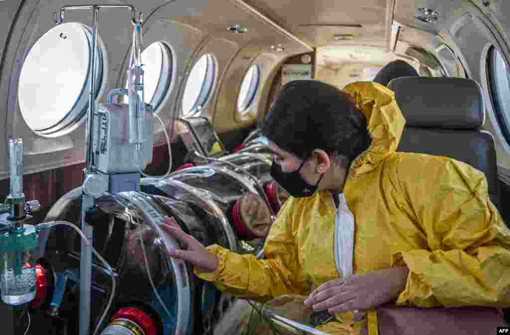 Andrea Lara (R) looks at her father Juan Carlos Lara, 59, a patient with COVID-19, as he is transferred inside a security capsule on an air ambulance from Iquitos to the Intensive Care Unit of the Rebagliati Hospital, in Lima, Peru.