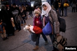 A Syrian girl carries her dolls as refugees and migrants arrive aboard a passenger ferry at the port of Piraeus, near Athens, Greece, Jan. 13, 2016.