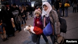 A Syrian girl carries her dolls as refugees and migrants arrive aboard a passenger ferry at the port of Piraeus, near Athens, Greece, Jan. 13, 2016.