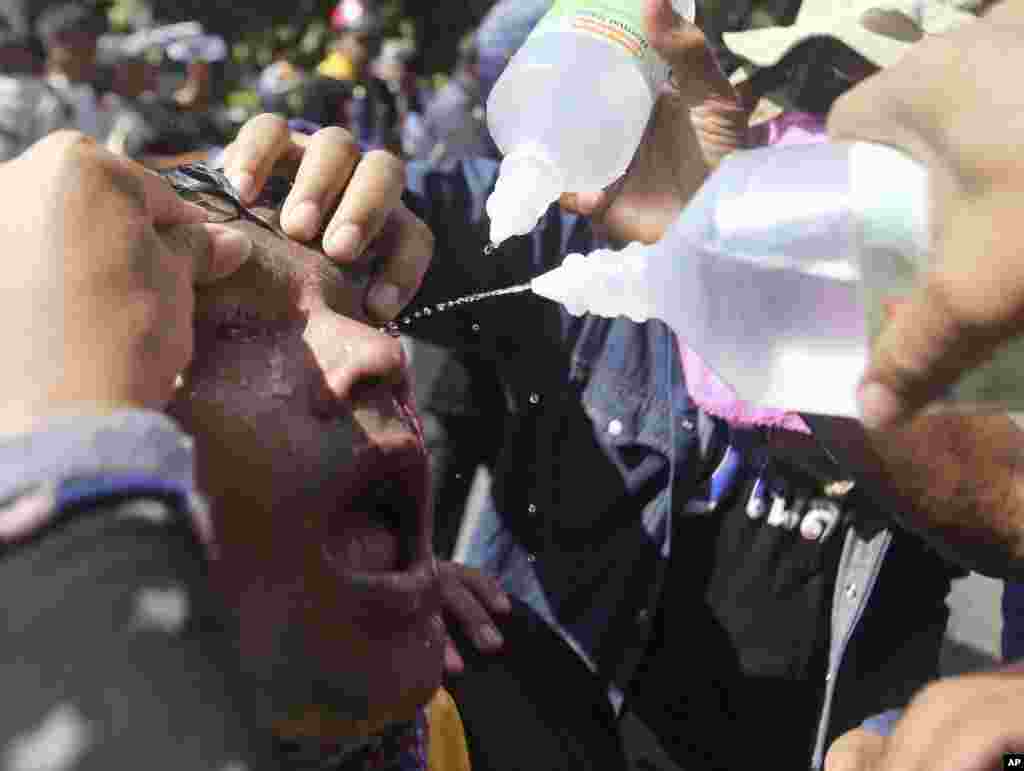 ရဲတပ်ဖွဲ့က ပစ်ခတ်လိုက်တဲ့ မျက်ရည်ယိုဗုံး ထိမှန်သွားတဲ့ အစိုးရဆန့်ကျင်ဆန္ဒပြသူရဲ့ မျက်လုံးကို ဆားရည်နဲ့ ဆေးကြောနေပုံ။ (ဘန်ကောက်)