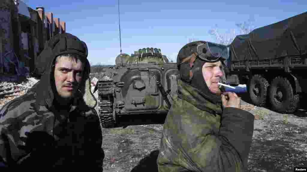 Fighters from the separatist-controlled Donetsk region smoke near an armored personnel carrier in the village of Nikishine, southeast of Debaltseve, Feb. 17, 2015. 