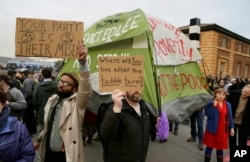 FILE - People hold up signs and a tent during a protest to demand city officials do more to help homeless people in San Francisco, California, Feb. 3, 2016.