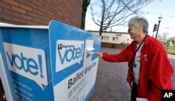 Barb Kearney-Schupp deposits her vote-by-mail ballot in a collection box, Thursday, Nov. 3, 2016, at Seattle Central College in Seattle. More than a million Washingtonians have already cast their ballots in advance of Tuesday's election, as voters decide on federal and state races, as well as ballot initiatives.