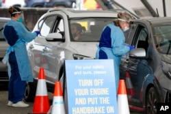 Personnel take samples for COVID-19 tests at a drive-thru testing facility set up in Bondi Beach, in Sydney, Australia, Jan. 8, 2022.