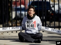 FILE - An Immigration activist, protesting deportations of people who are in the country illegally, blocks the front gate of a building that houses federal immigration authorities in Atlanta.