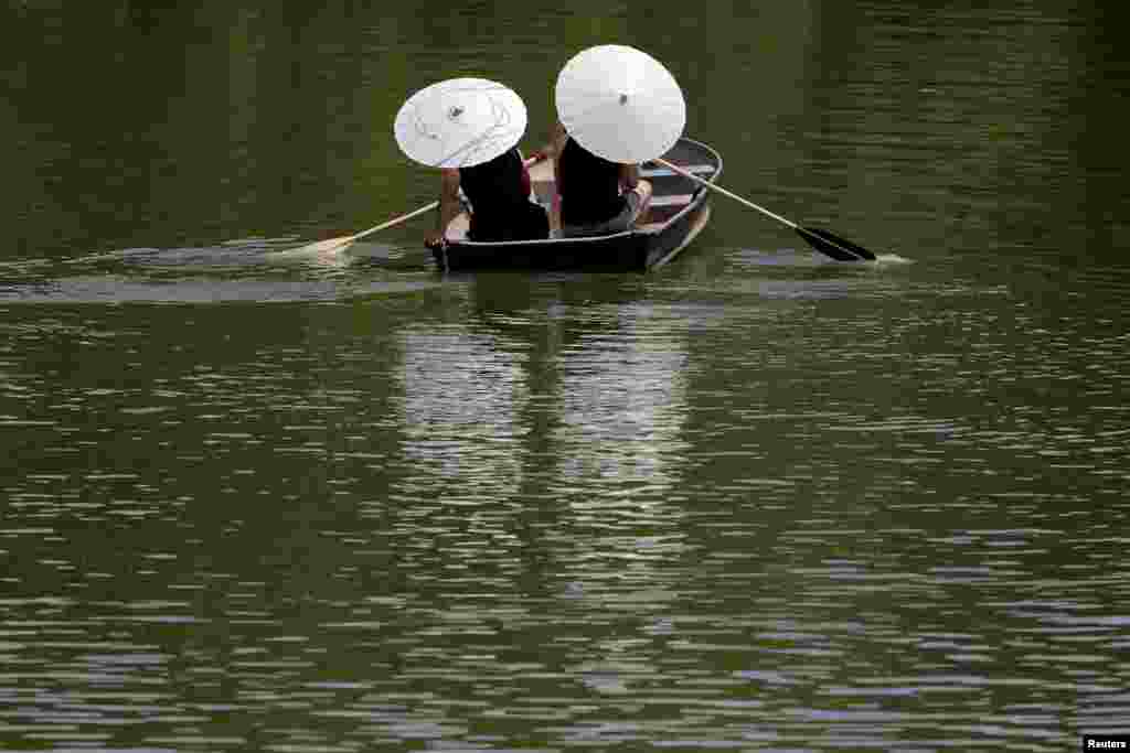 People protect themselves from the sun with parasols while rowing in Central Park as a heatwave continues to affect the region, in New York, U.S., July 21, 2019.