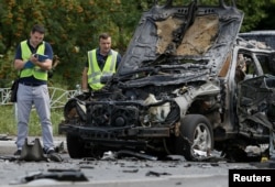 FILE - Investigators work at the scene of a car bomb explosion which killed Maksim Shapoval, a high-ranking official involved in military intelligence, in Kyiv, Ukraine, June 27, 2017.