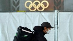 An Uber Eats delivery person carries items near the Japan National Stadium, where opening ceremony and other events are planned for postponed Tokyo 2020 Olympics, on Tuesday, April 6, 2021, in Tokyo. (AP Photo/Eugene Hoshiko)