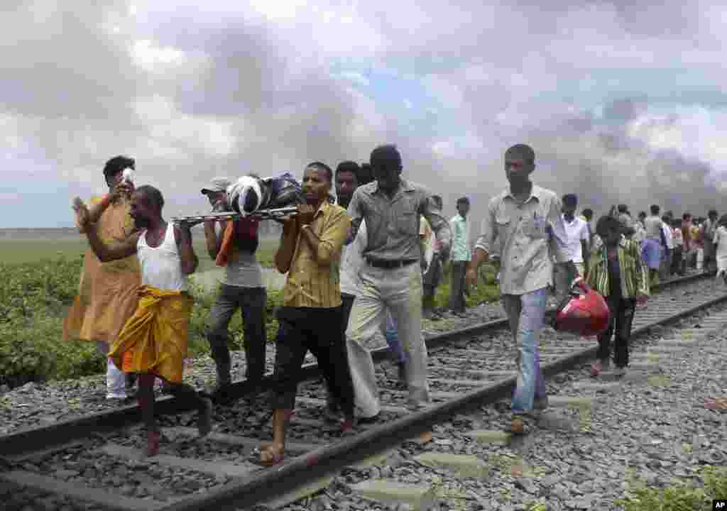 Villagers carry an injured person after a train ran over a group of Hindu pilgrims at a crowded station in Dhamara Ghat, Bihar state, India, August 19, 2013. 