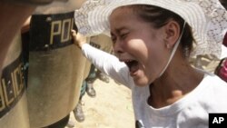 A Cambodian protester, right, from Boueng Kak lake, cries as she clashes with police officers in Phnom Penh, Cambodia, Tuesday, May 22, 2012. 