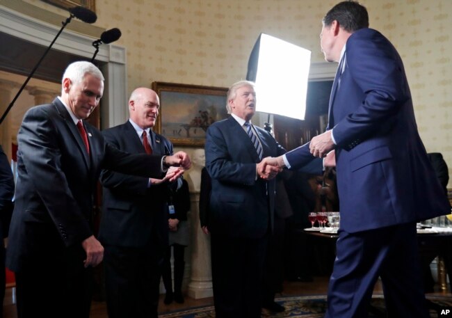 FILE - President Donald Trump (2-R) shakes hands with then-FBI Director James Comey (R) in the Blue Room of the White House in Washington, Jan. 22, 2017, as Vice President Mike Pence (L) and Secret Service Director Joseph Clancy look on. Trump fired Comey in May of that year.