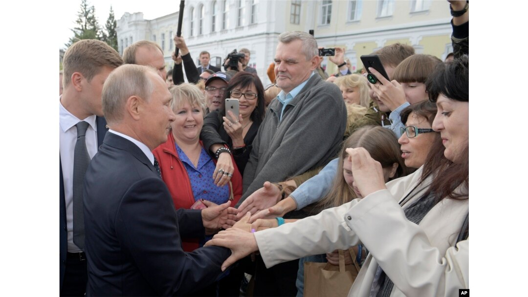 FILE - Russian President Vladimir Putin, left, greets local residents in Omsk, Russia, Aug. 28, 2018.