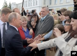 FILE - Russian President Vladimir Putin, left, greets local residents in Omsk, Russia, Aug. 28, 2018.