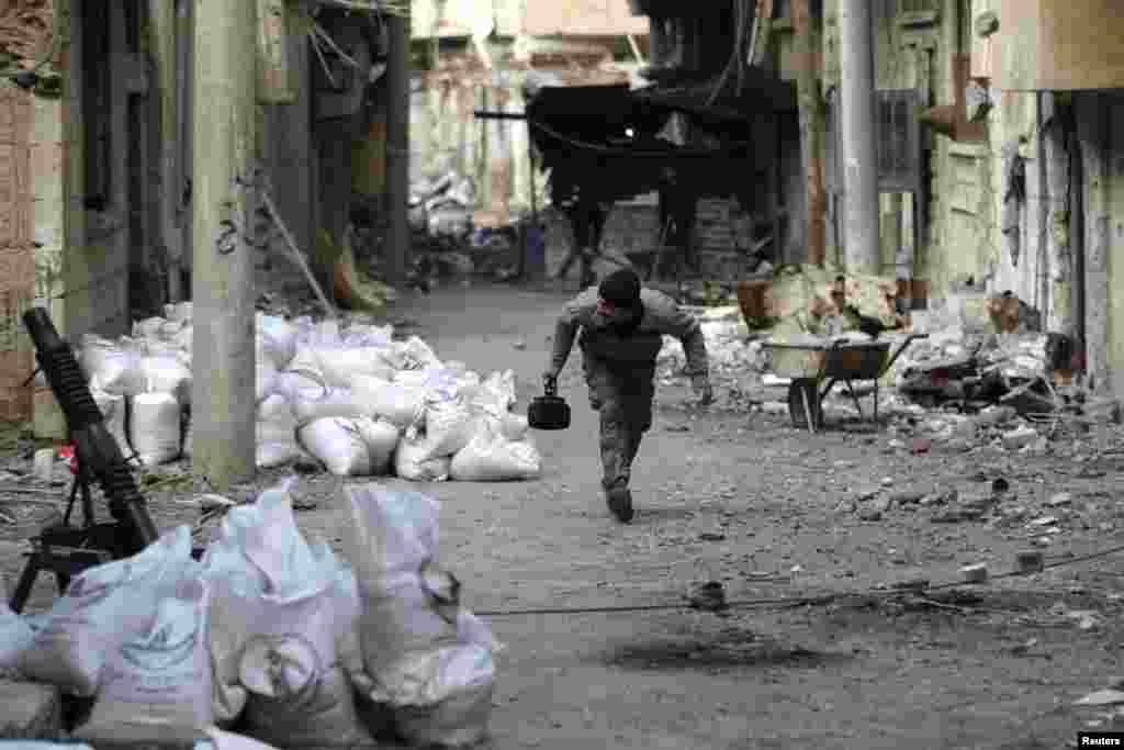A Free Syrian Army fighter holds a teapot as he runs to avoid snipers in Deir al-Zor, Feb. 4, 2014. 