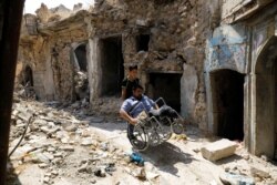 Mohammed Sattar duduk di kursi roda di samping rumahnya yang hancur di kota tua Mosul, Irak, 31 Agustus 2020. (Foto: REUTERS/Khalid al-Mousily)
