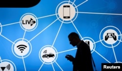 A man looks at his phone in front of a stand at the Mobile World Congress in Barcelona, Spain, showing a variety of devices connected via Wi-Fi and Internet of Things networks, Feb. 28, 2017