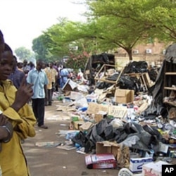 Residents look at debris on the pavement on April 16, 2011 in Ouagadougou after soldiers from three barracks took to the streets of the Burkina Faso capital overnight, firing into the air and pillaging as a mutiny entered its third day