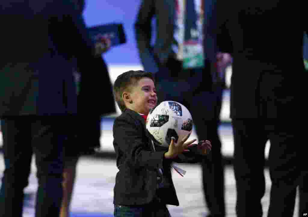 A young boy holds the official ball as he stands on stage after the 2018 soccer World Cup draw in the Kremlin in Moscow.