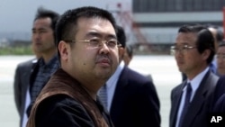 FILE - A man believed to be Kim Jong Nam, the eldest son of North Korean leader Kim Jong Il, looks at a battery of photographers as he exits a police van to board a plane to Beijing at Narita International Airport, northeast of Tokyo, May 4, 2001. 