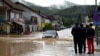 People watch a car in a flooded street in Kiseljak, Bosnia-Herzegovina, Oct. 4, 2024.