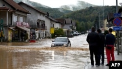 People watch a car in a flooded street in Kiseljak, Bosnia-Herzegovina, Oct. 4, 2024.