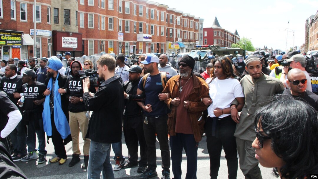 Civilians linked arms, separating police officers and restive demonstrators on a mostly peaceful afternoon in Baltimore, Maryland, April 28, 2015. (VOA photo/ Victoria Macchi)